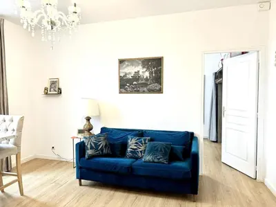 a blue couch in a living room with a chandelier at Lumineux appartement deux pièces in Nice