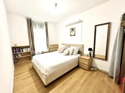 a white bedroom with a bed and a mirror at Lumineux appartement deux pièces in Nice