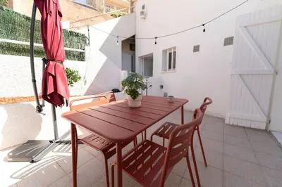 a wooden table and chairs on a patio with an umbrella at La Tanière du Bois Flotté in Nice