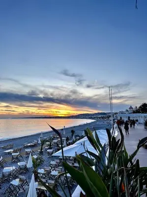 a beach with umbrellas and people on the sand at La Tanière du Bois Flotté in Nice