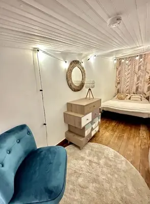 a living room with a blue chair and a bed at La Tanière du Bois Flotté in Nice