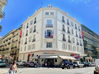 a tall white building on a city street with cars at Résidence de l'Alliance in Nice