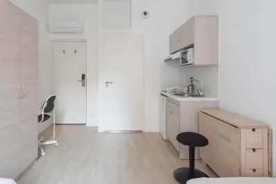 a small white kitchen with a sink and a stool at Résidence de l'Alliance in Nice