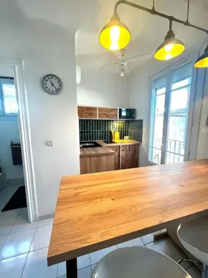 a kitchen with a wooden table and a clock on the wall at Studio de charme hyper centre in Nice