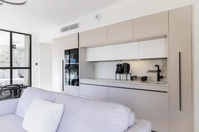a white living room with a couch and a kitchen at SPLENDIDE APPARTEMENT NICE BLUE PEARL TOUT CONFORT VUE MER PANORAMIQUE in Nice