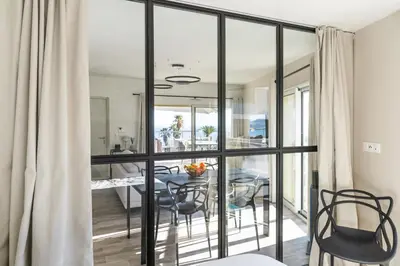 a dining room with glass doors and a table with chairs at SPLENDIDE APPARTEMENT NICE BLUE PEARL TOUT CONFORT VUE MER PANORAMIQUE in Nice