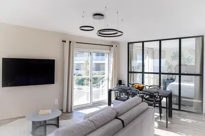 a living room with a couch and a table with chairs at SPLENDIDE APPARTEMENT NICE BLUE PEARL TOUT CONFORT VUE MER PANORAMIQUE in Nice
