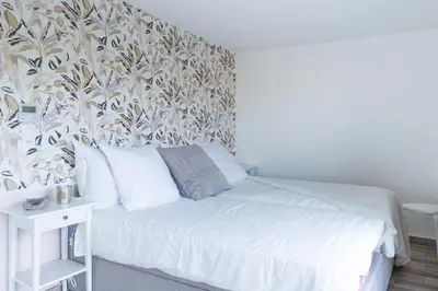 a bedroom with a white bed with a floral wallpaper at SPLENDIDE APPARTEMENT NICE BLUE PEARL TOUT CONFORT VUE MER PANORAMIQUE in Nice