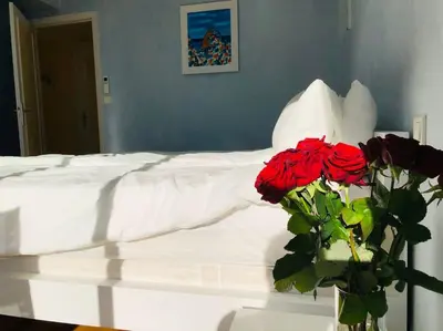 a bedroom with a bed with red roses in a vase at Appartement „Bellevue“ Villefranche-sur-Mer in Villefranche-sur-Mer
