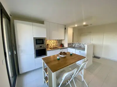 a kitchen with a wooden table and white cabinets at Nice Ouest- 2P au Calme, Piscine, AC in Nice