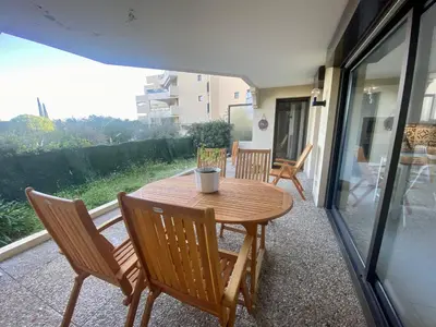 a wooden table and chairs on a patio at Nice Ouest- 2P au Calme, Piscine, AC in Nice