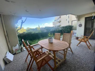 a wooden table and chairs on a patio at Nice Ouest- 2P au Calme, Piscine, AC in Nice