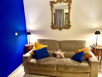 a brown couch with blue and yellow pillows and a mirror at SuperbeStudio in Nice - 450m of the sea- garden view in Nice