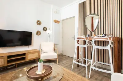 a living room with a tv and two white stools at L46 2P Port, 2min du Cap et 5 du port/ CLIM & WIFI in Nice