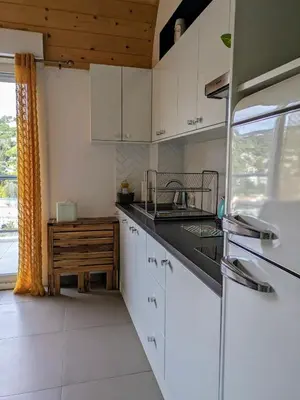 a kitchen with white cabinets and a sink and a window at Studio calme avec vue dégagée in Nice