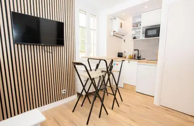 a kitchen with a table with chairs and a television on a wall at Cozy studio in Villefranche-sur-Mer in Villefranche-sur-Mer