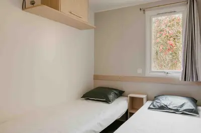 two beds in a small room with a window at Camping VAL FLEURI ATC Cagnes-Sur-Mer in Cagnes-sur-Mer