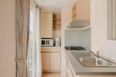 a white kitchen with a sink and a microwave at Camping VAL FLEURI ATC Cagnes-Sur-Mer in Cagnes-sur-Mer