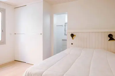 a white bedroom with a bed and a refrigerator at Camping VAL FLEURI ATC Cagnes-Sur-Mer in Cagnes-sur-Mer