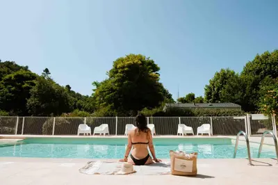 a woman in a bikini sitting next to a swimming pool at Camping VAL FLEURI ATC Cagnes-Sur-Mer in Cagnes-sur-Mer