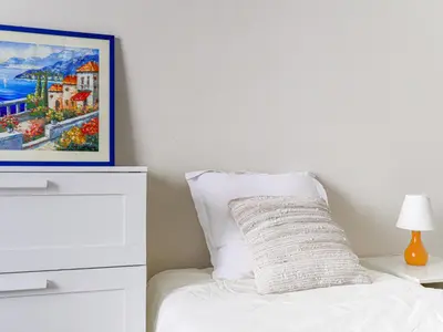 a bedroom with a white bed with a painting on the wall at Apartment Le Victor Hugo by Interhome in Nice