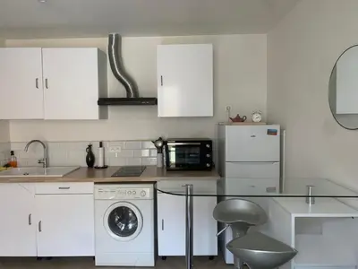 a kitchen with white cabinets and a glass table at Charmant Appartement à 5 minutes de la plage in Nice