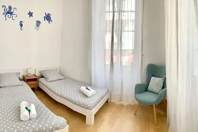 a bedroom with two beds and a blue chair at Saint Philippe - T3 près de la plage in Nice