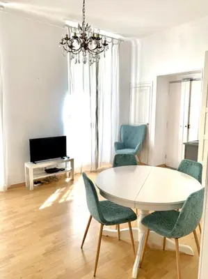 a living room with a table and chairs and a television at Saint Philippe - T3 près de la plage in Nice