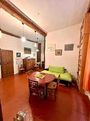 a living room with a table and a green bed at Abbaye - Appartement spacieux au coeur du Vieux-Nice in Nice