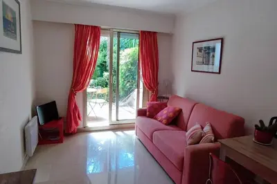 a living room with a red couch and a sliding glass door at Ratti - Studio avec jardin au coeur de Nice in Nice