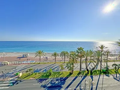 a view of a beach with palm trees and the ocean at Cosy Sea Front Apartment Nice France in Nice