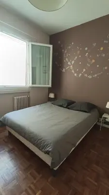 a bedroom with a bed and a wall with a tree mural at Appartement quartier Libération in Nice