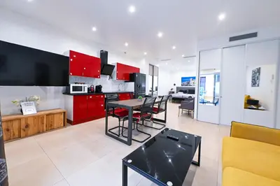 a kitchen with red cabinets and a table and chairs at Grand loft à deux pas de la mer n1 in Nice