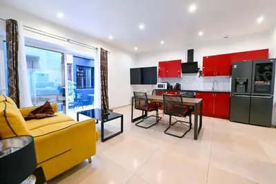 a living room with a yellow couch and a kitchen with red cabinets at Grand loft à deux pas de la mer n1 in Nice