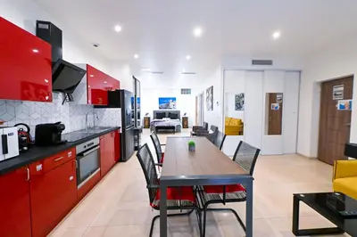 a kitchen with red cabinets and a table and chairs at Grand loft à deux pas de la mer n1 in Nice