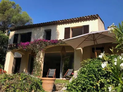 a house with two chairs and an umbrella at Villa de Charme au coeur du Cap-Ferrat in Saint-Jean-Cap-Ferrat