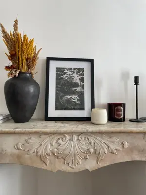 a black vase sitting on a shelf with a picture at Appartement à 1 min de la plage in Nice