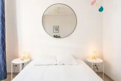 a white bedroom with a large mirror on the wall at #21 2 Bdr balconies 10 mins walk to sea 5mins to tram in Nice
