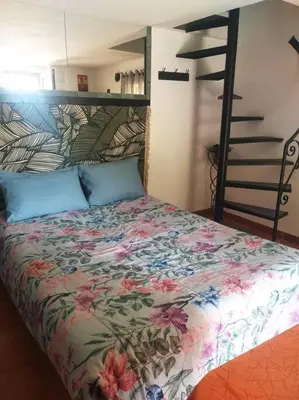a bedroom with a bed with a floral bedspread and a ladder at Au lit, on dort in Cantaron