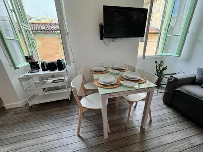 a table and chairs in a living room with a tv at Carre D'or: Very Central Calm Cozy 2BR, with Wi-Fi in Nice