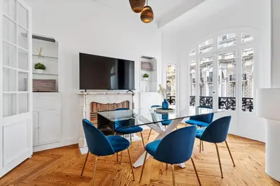 a dining room with a glass table and blue chairs at Nice Renting - FOCH - Luxury Bourgeois & Design at the Heart of Nice in Nice