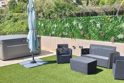 a patio with an umbrella and chairs and a couch and a table at 2p bas de Villa avec Jacuzzi privatif proche de Nice in Saint-Laurent-du-Var