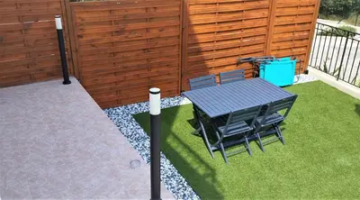a patio with a table and chairs on the grass at 2p bas de Villa avec Jacuzzi privatif proche de Nice in Saint-Laurent-du-Var