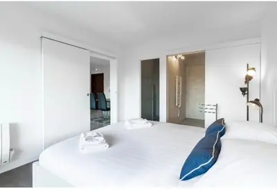 a white bedroom with a large white bed with blue pillows at Nice Absea Belles Terres in Nice