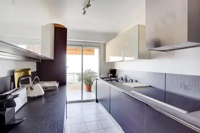 a kitchen with white and black cabinets and a sink at Nice Absea Belles Terres 5 in Nice