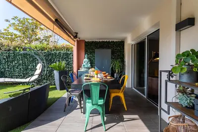 a patio with a table and chairs on a patio at DOMAINE DES ROSES 3 AP4400 By Riviera Holiday Home in Nice