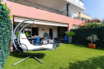 a couple of chairs sitting on the grass in a yard at DOMAINE DES ROSES 3 AP4400 By Riviera Holiday Home in Nice