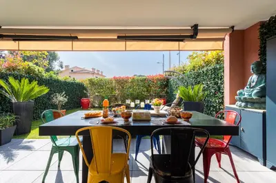 a table and chairs on a patio with a view of a garden at DOMAINE DES ROSES 3 AP4400 By Riviera Holiday Home in Nice