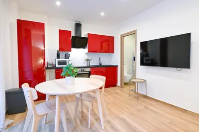 a kitchen with red cabinets and a table with chairs at Beau studio cozy centre ville et plages avec terrasse n3 in Nice