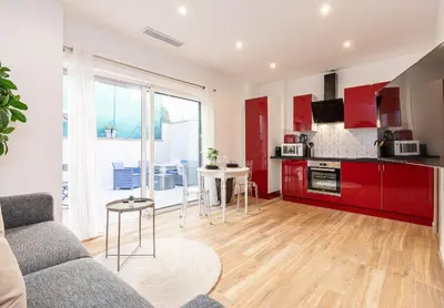 a living room with a couch and a kitchen with red cabinets at Beau studio cozy centre ville et plages avec terrasse n3 in Nice